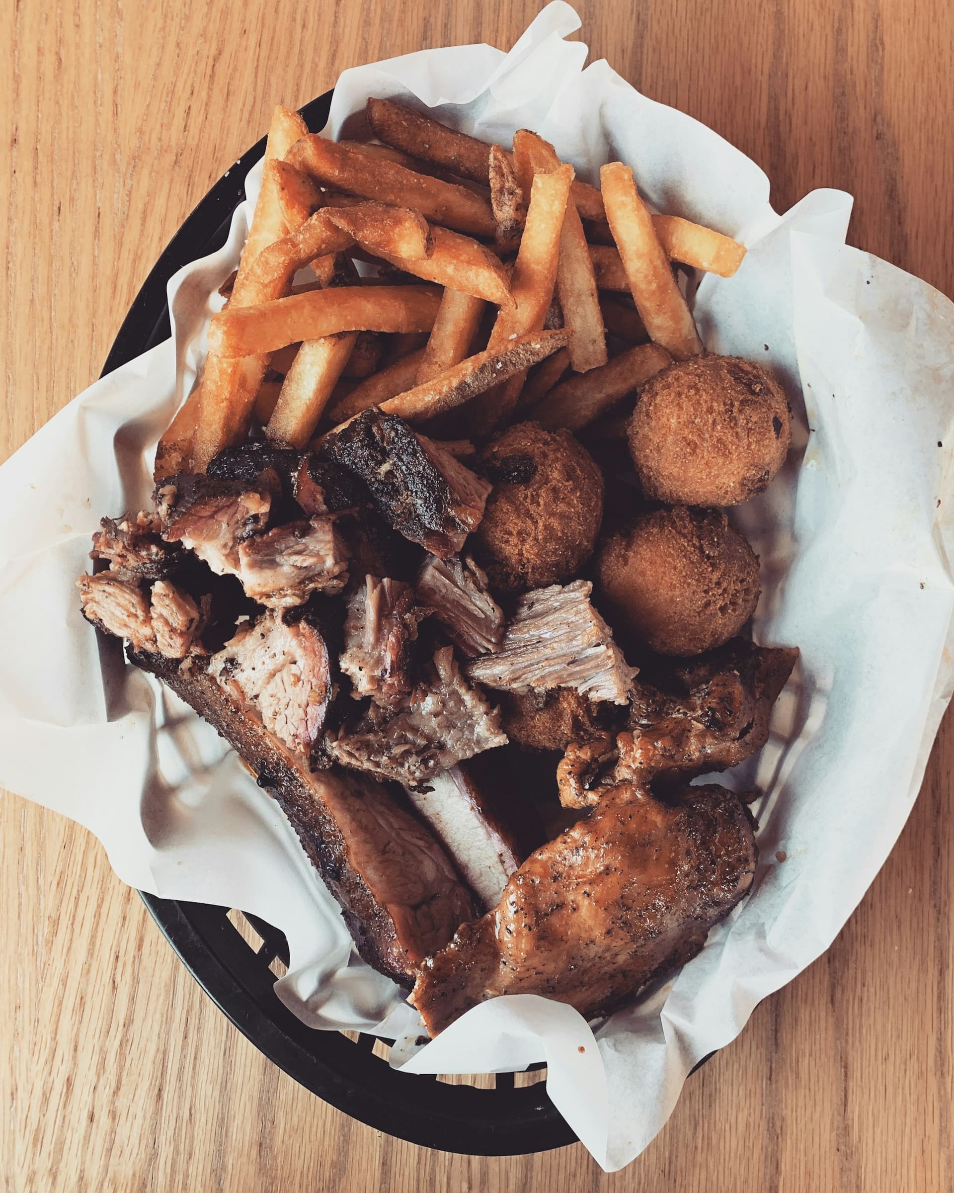 Basket of burnt ends with hush puppies and hand-cut fries on butcher paper