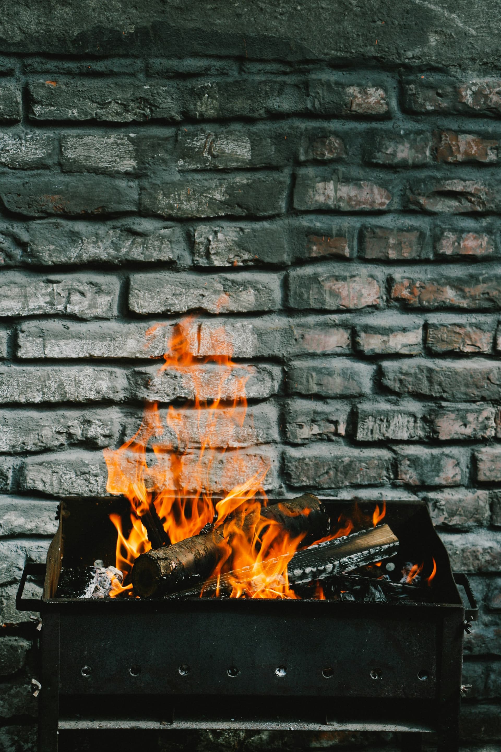 Oak splits burning down to coals against the black brick of the pit room