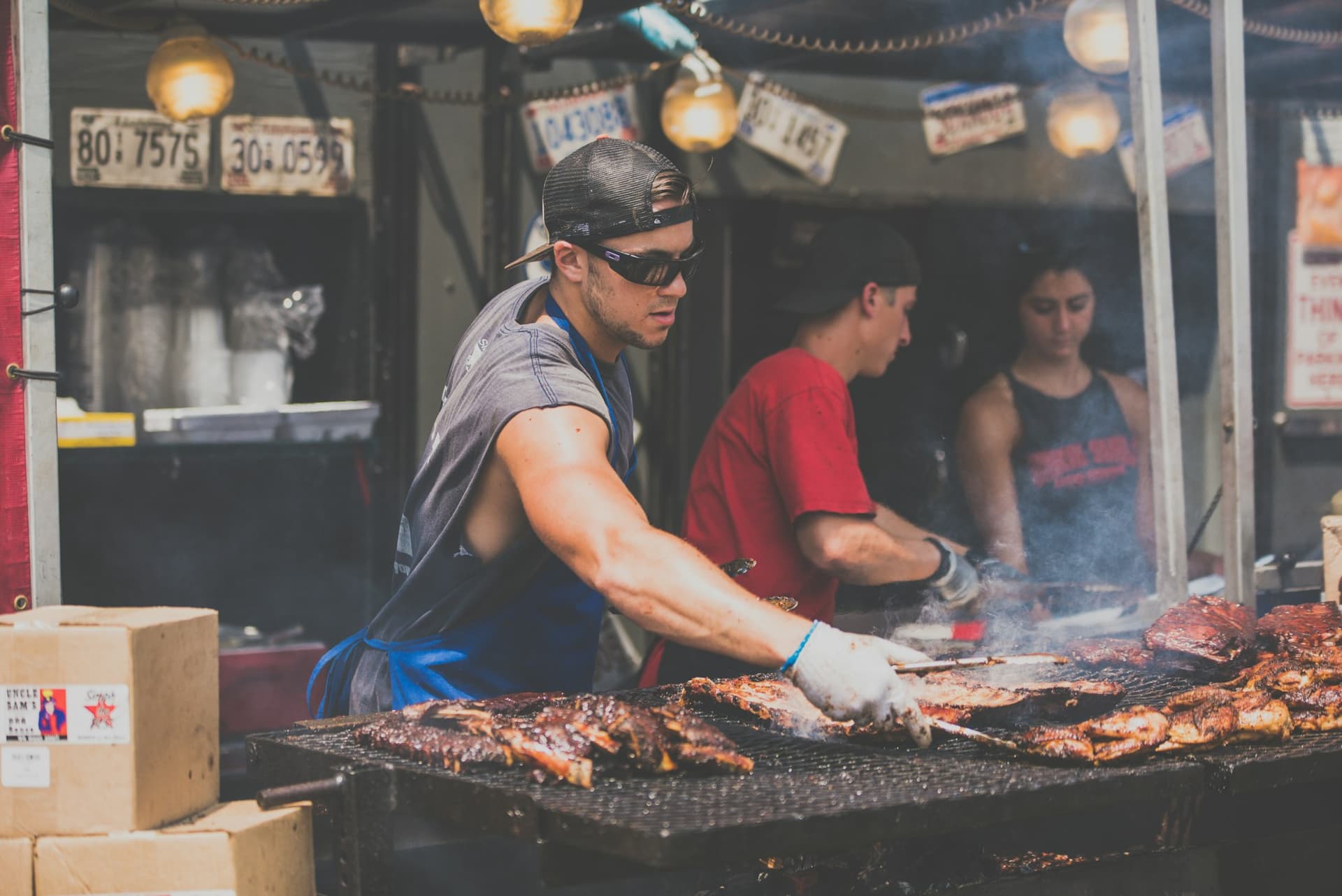 The Emberline crew working a packed grill line in the smoke, tongs out