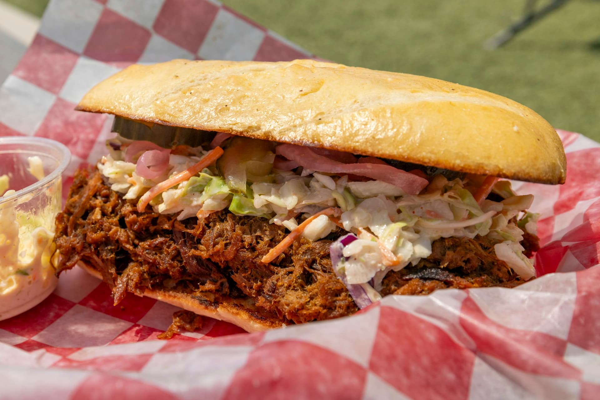The Slow Pull sandwich piled with pulled pork, vinegar slaw and pickled onions